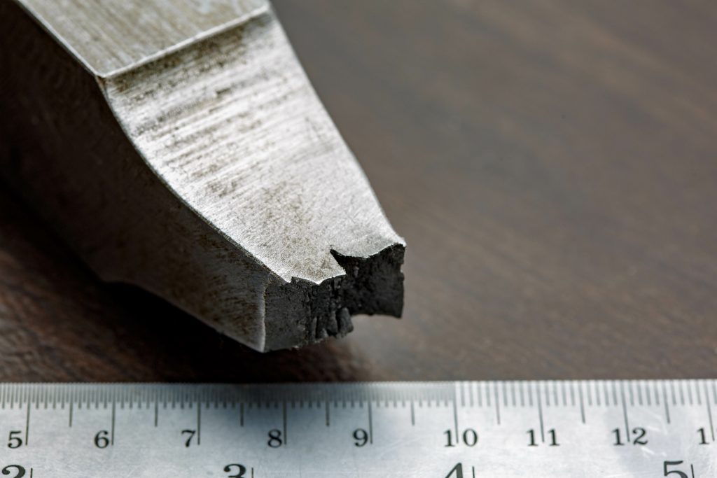 Fractured end of a metal tensile specimen next to a measuring rule
