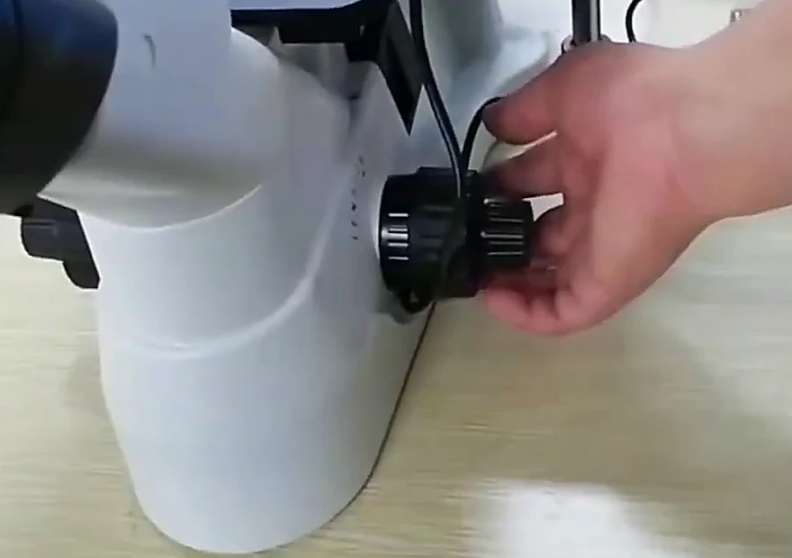 Operator turning the coaxial coarse and fine focus knobs on the G-800E stand
